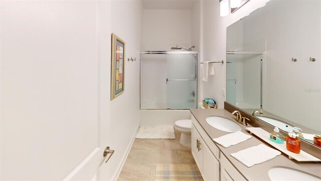 8851 Fallen Oak Dr, Davenport, FL 33896 - full bathroom featuring tile patterned floors, toilet, vanity, bath / shower combo with glass door, and baseboards