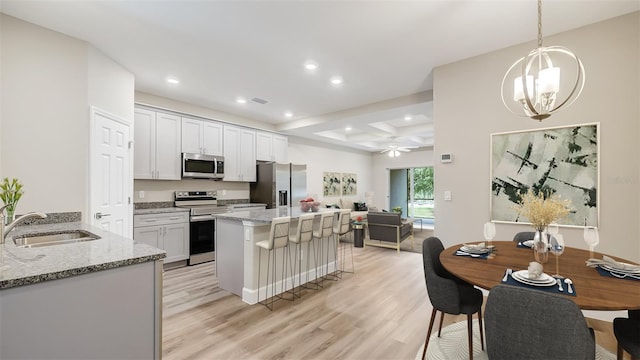 8560 Magnificent Ln, Groveland, FL 34736 - kitchen with stainless steel appliances, a sink, light wood-style floors, a kitchen island, and ceiling fan