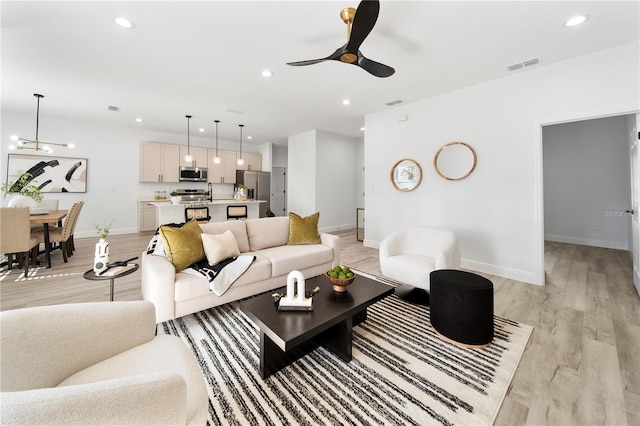 living room with light wood finished floors, ceiling fan, baseboards, and recessed lighting