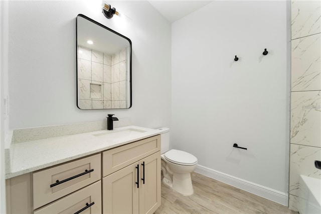 full bathroom with wood finished floors, toilet, vanity, a shower, and baseboards