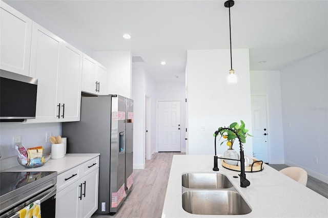 921 Sable Cir SE, Palm Bay, FL 32909 - kitchen with stainless steel appliances, a sink, light wood-style flooring, pendant lighting, and baseboards