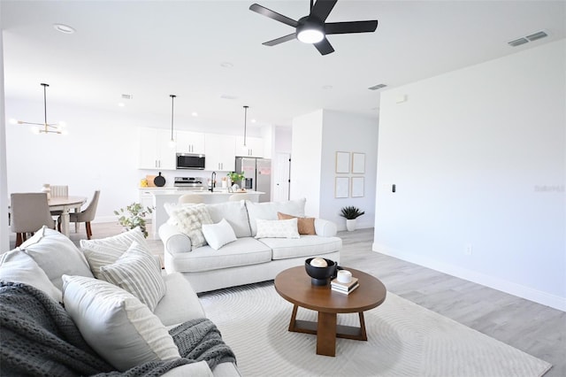 921 Sable Cir SE, Palm Bay, FL 32909 - living room featuring light wood finished floors, ceiling fan, a chandelier, baseboards, and recessed lighting