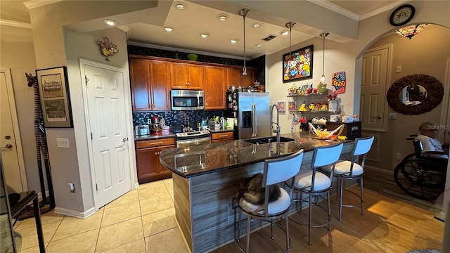 kitchen with appliances with stainless steel finishes, a sink, crown molding, a breakfast bar area, and tasteful backsplash