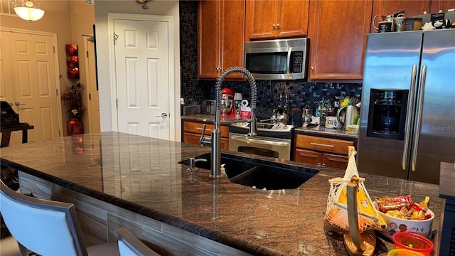 kitchen with stainless steel appliances, decorative backsplash, and dark stone countertops