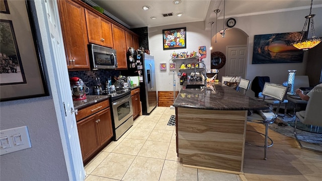kitchen featuring appliances with stainless steel finishes, crown molding, a breakfast bar area, a sink, and backsplash