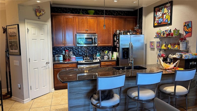 kitchen featuring stainless steel appliances, ornamental molding, a breakfast bar area, light tile patterned floors, and tasteful backsplash