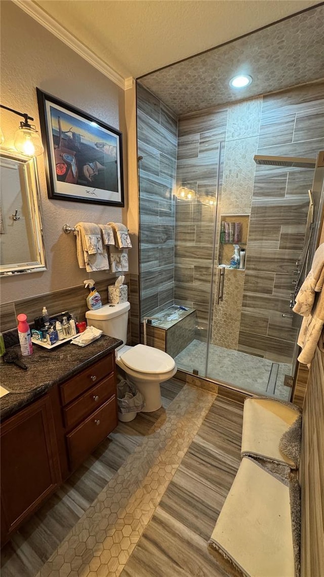 bathroom with toilet, ornamental molding, vanity, a shower stall, and tile patterned floors