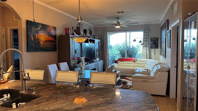 dining area with a ceiling fan, arched walkways, wood finished floors, and ornamental molding