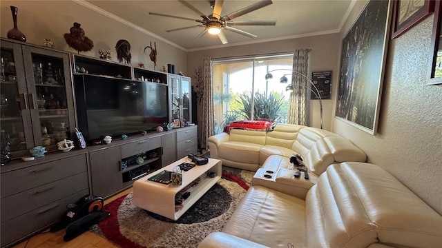 living room with ceiling fan, ornamental molding, a textured wall, and wood finished floors