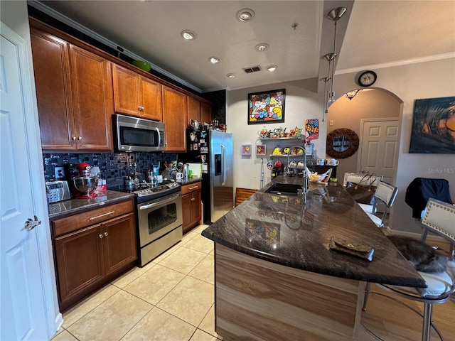 kitchen featuring stainless steel appliances, crown molding, a kitchen breakfast bar, tasteful backsplash, and a sink