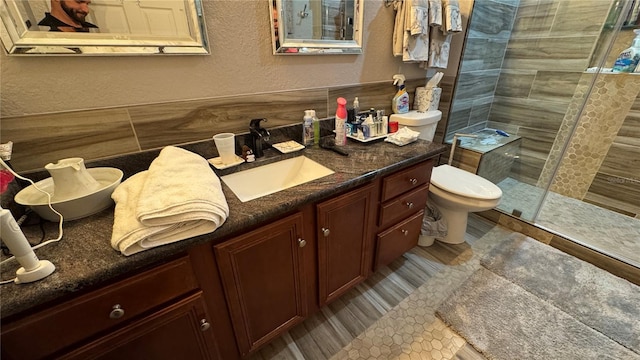 full bathroom with a textured wall, tiled shower, toilet, tasteful backsplash, and vanity