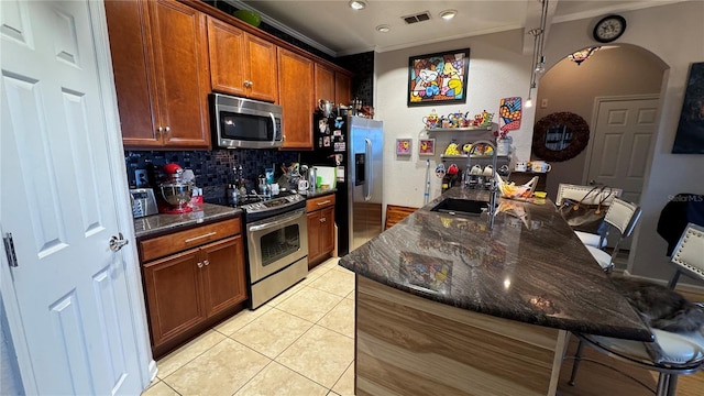 kitchen featuring appliances with stainless steel finishes, crown molding, a breakfast bar area, a sink, and decorative backsplash