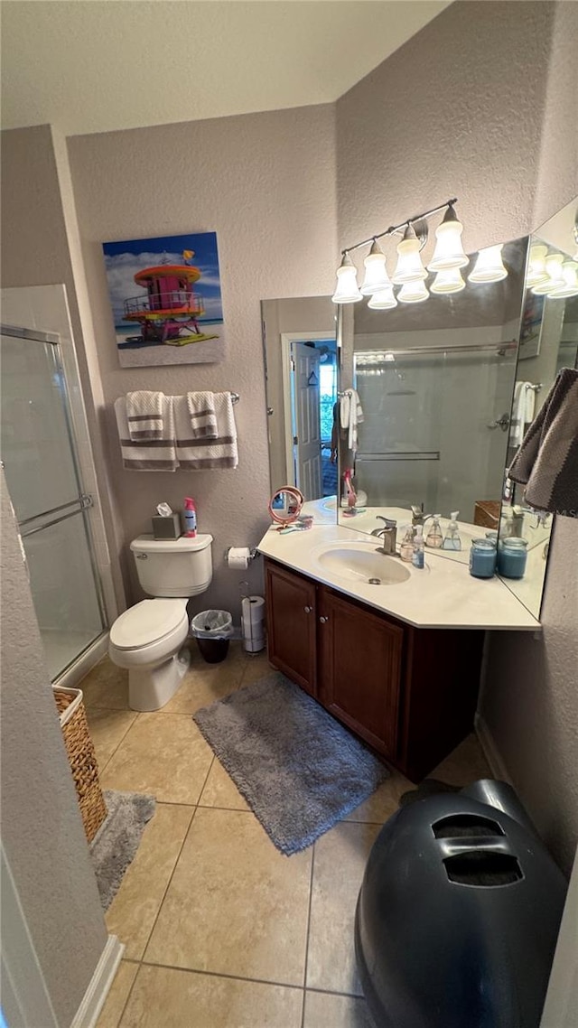 full bath with a textured wall, a stall shower, tile patterned floors, toilet, and vanity
