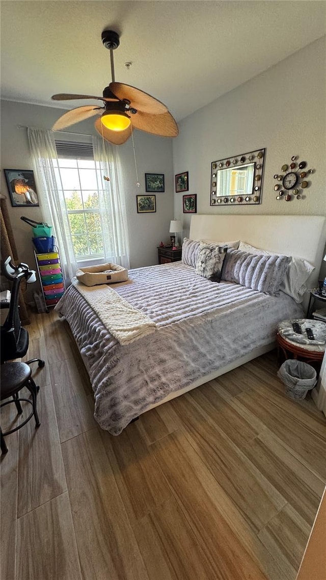 bedroom with wood finished floors, vaulted ceiling, and a ceiling fan