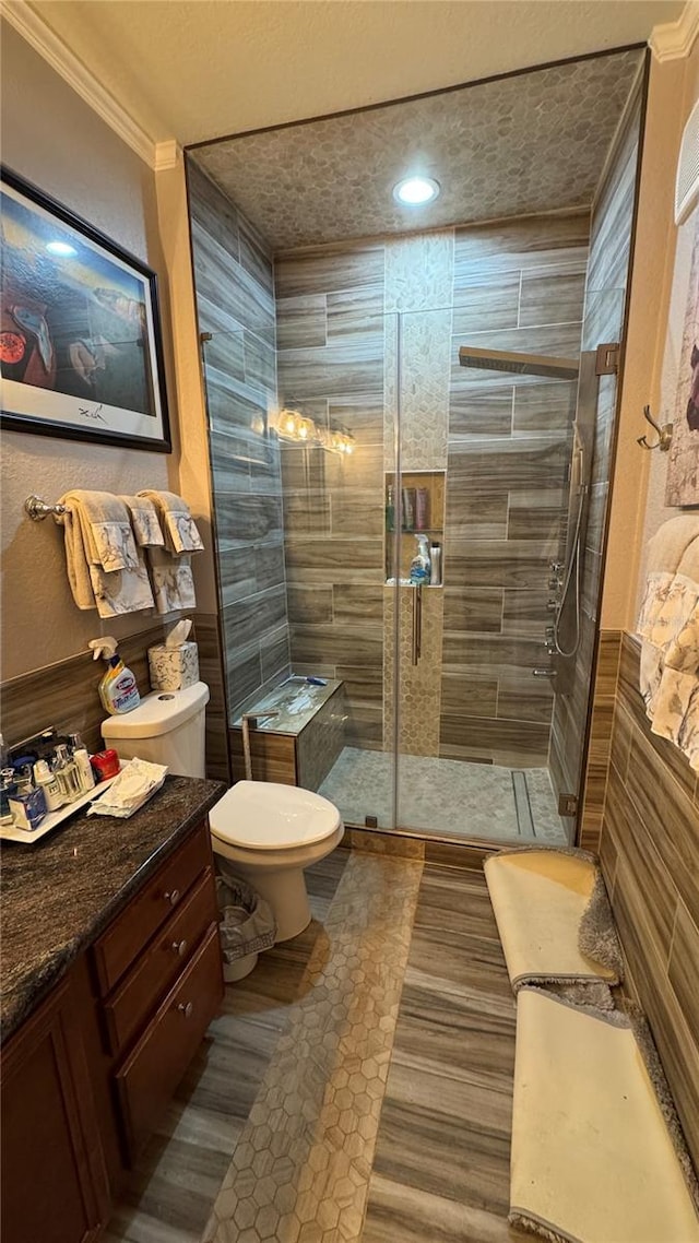 bathroom featuring toilet, a tile shower, vanity, crown molding, and a textured ceiling