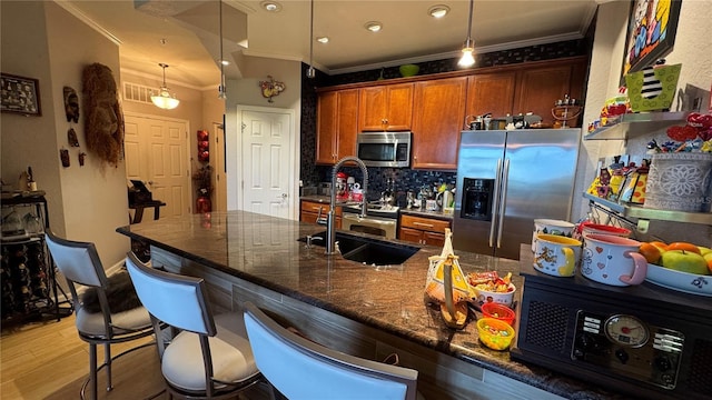kitchen with appliances with stainless steel finishes, crown molding, tasteful backsplash, light wood finished floors, and a breakfast bar area