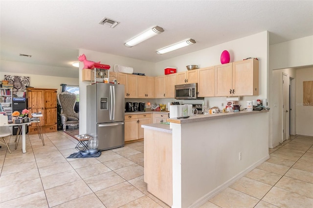 kitchen featuring stainless steel appliances, light brown cabinets, light countertops, light tile patterned floors, and a peninsula