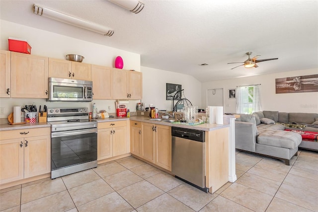 kitchen featuring appliances with stainless steel finishes, light brown cabinetry, a peninsula, open floor plan, and ceiling fan