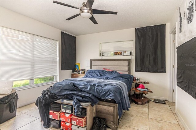 bedroom featuring light tile patterned floors, ceiling fan, a textured ceiling, and baseboards