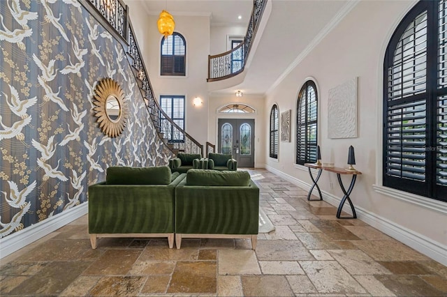 entryway with stone tile floors, healthy amount of natural light, baseboards, a high ceiling, and ornamental molding