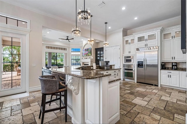 kitchen with stainless steel appliances, stone tile floors, recessed lighting, ornamental molding, and white cabinetry
