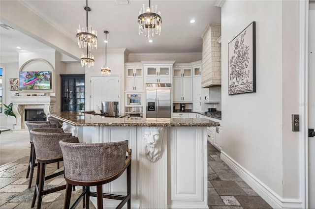 kitchen with stainless steel appliances, stone tile flooring, baseboards, crown molding, and white cabinetry