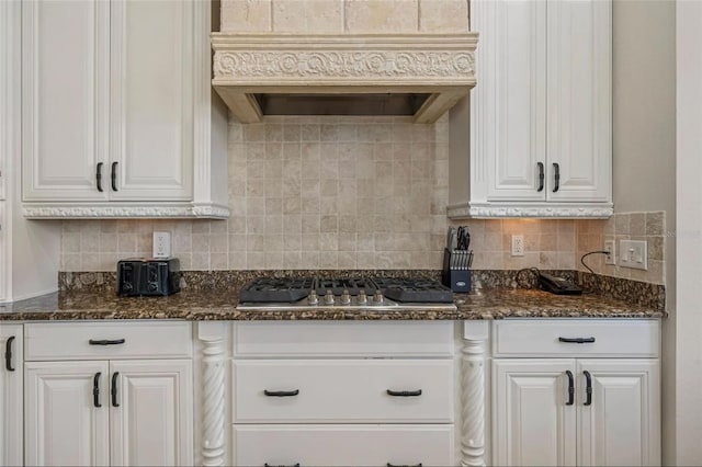 kitchen featuring stainless steel gas cooktop, premium range hood, white cabinets, and backsplash