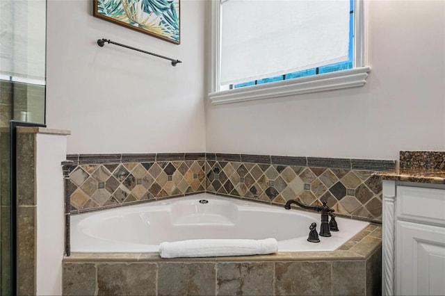 bathroom with vanity, a bath, and tiled shower