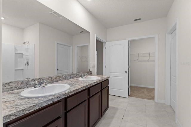 979 Sun Burst Rd, Winter Haven, FL 33880 - bathroom with double vanity, tile patterned floors, a shower, a spacious closet, and baseboards