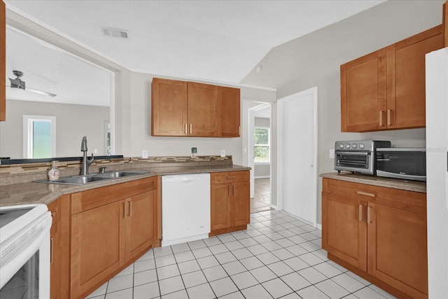 3685 Sunday Dr, Deltona, FL 32738 - kitchen featuring white appliances, a sink, light tile patterned floors, brown cabinetry, and vaulted ceiling