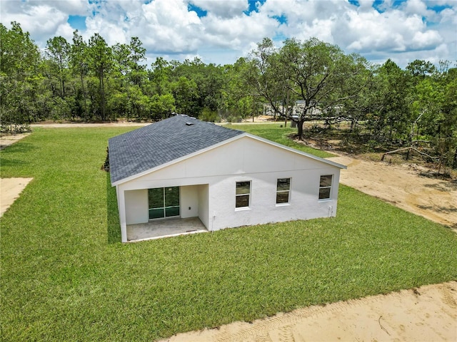 8258 SW 136th Ter, Dunnellon, FL 34432 - rear view of property featuring a shingled roof, stucco siding, a lawn, and a patio