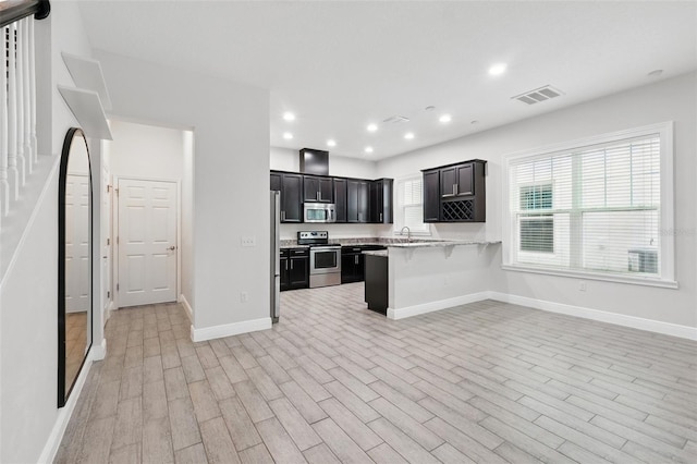 kitchen with appliances with stainless steel finishes, light countertops, light wood-style floors, open floor plan, and baseboards