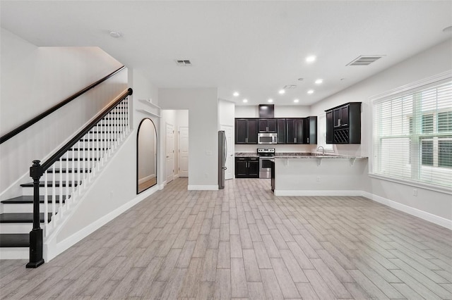 kitchen with appliances with stainless steel finishes, baseboards, light wood-style floors, light countertops, and recessed lighting