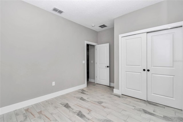 9695 SW 125 Court Rd, Dunnellon, FL 34432 - unfurnished bedroom featuring light wood finished floors, a closet, baseboards, and a textured ceiling