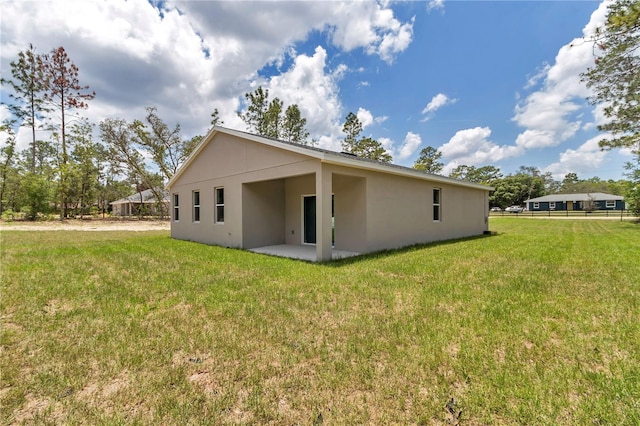 9695 SW 125 Court Rd, Dunnellon, FL 34432 - rear view of house featuring stucco siding, a yard, and a patio