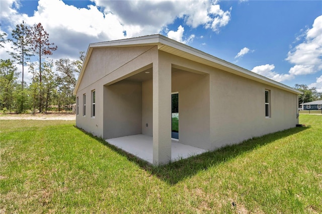 9695 SW 125 Court Rd, Dunnellon, FL 34432 - view of home's exterior featuring stucco siding, a patio, and a yard