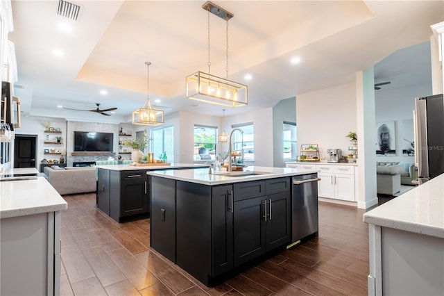 kitchen featuring a sink, appliances with stainless steel finishes, an island with sink, open floor plan, and a ceiling fan