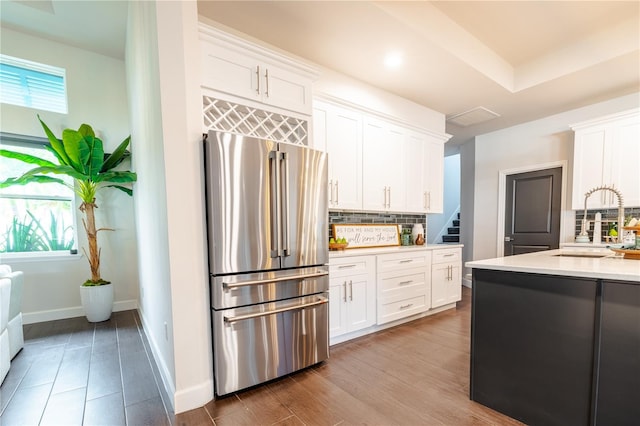 kitchen with freestanding refrigerator, decorative backsplash, light countertops, white cabinets, and a sink