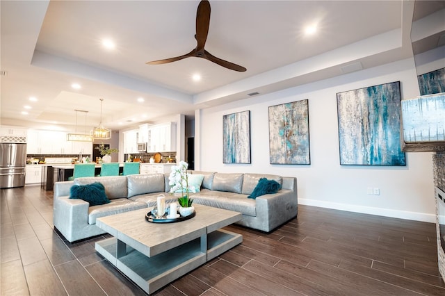 living room featuring a raised ceiling, baseboards, ceiling fan, wood finish floors, and recessed lighting
