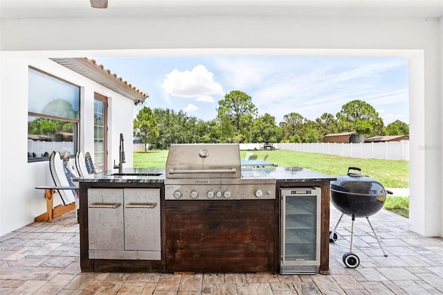 view of patio / terrace featuring beverage cooler, an outdoor kitchen, a sink, and area for grilling
