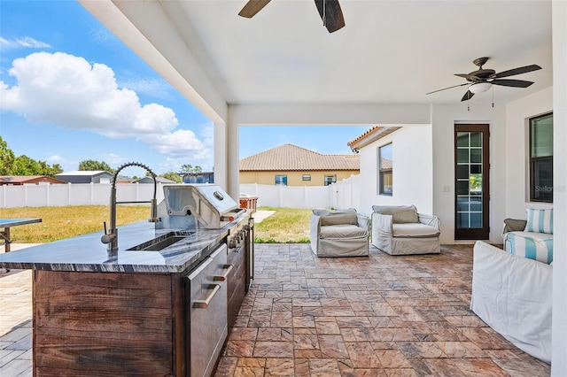 view of patio / terrace with a ceiling fan, an outdoor kitchen, and a sink