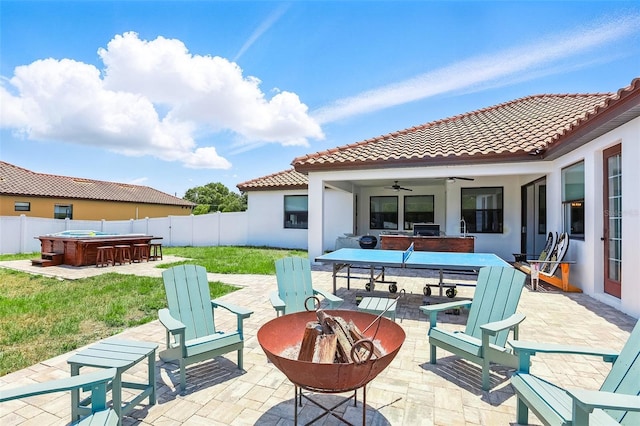 view of patio / terrace featuring a hot tub, a ceiling fan, outdoor dining space, and a fire pit