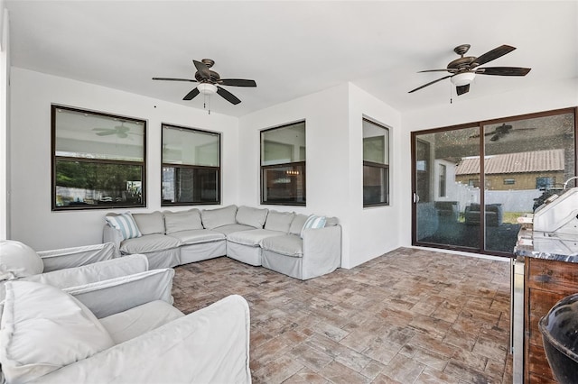 living area with a ceiling fan and brick patterned flooring