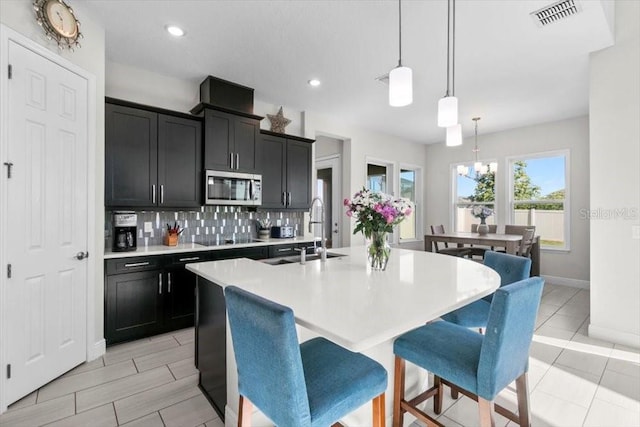 14639 Winter Stay Dr, Winter Garden, FL 34787 - kitchen with stainless steel microwave, black electric cooktop, a sink, light countertops, and backsplash