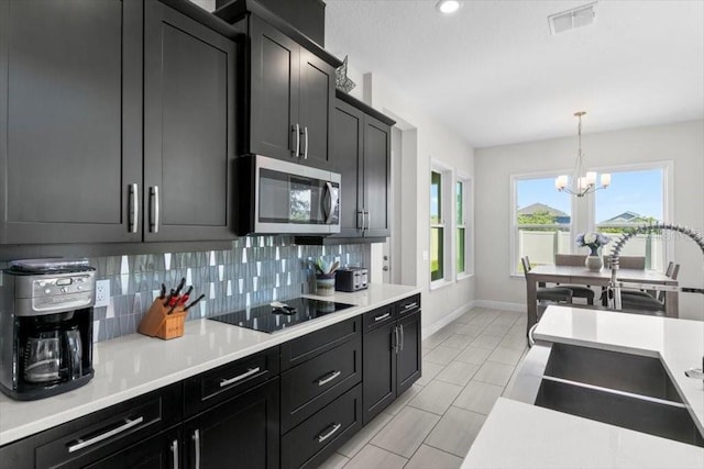 14639 Winter Stay Dr, Winter Garden, FL 34787 - kitchen featuring stainless steel microwave, black electric cooktop, a sink, baseboards, and backsplash