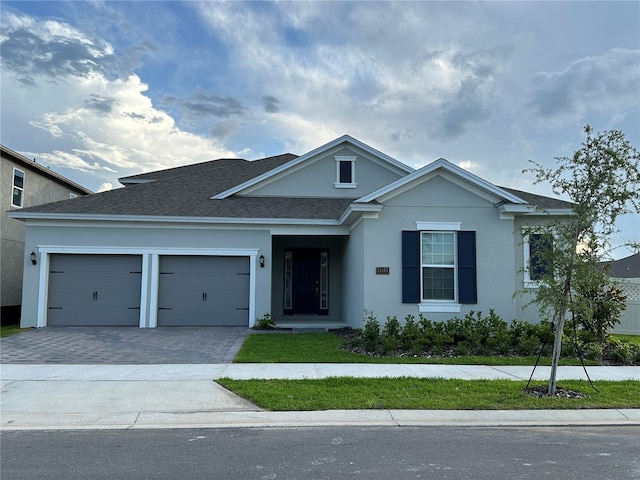 view of front of home featuring decorative driveway, stucco siding, an attached garage, and a shingled roof