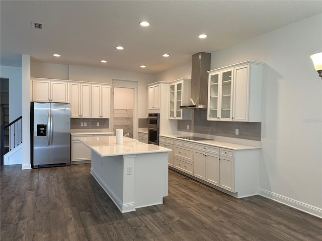 kitchen with stainless steel appliances, wall chimney exhaust hood, dark wood-type flooring, decorative backsplash, and light countertops