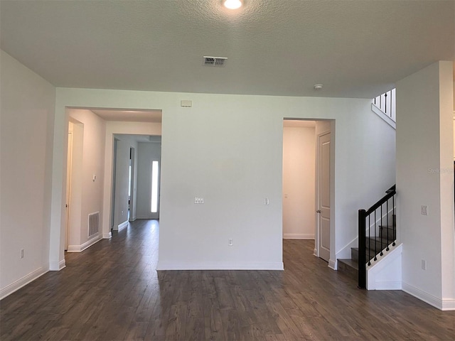 unfurnished living room with dark wood-type flooring, stairs, and baseboards