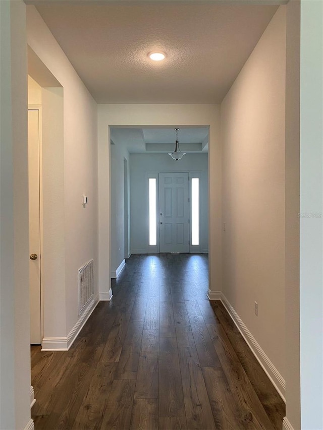 entrance foyer with dark wood-style floors, baseboards, and a textured ceiling