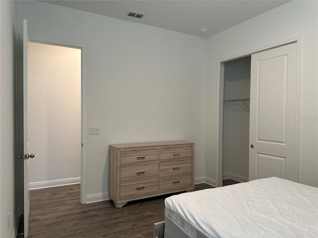 bedroom with dark wood finished floors, baseboards, and a closet